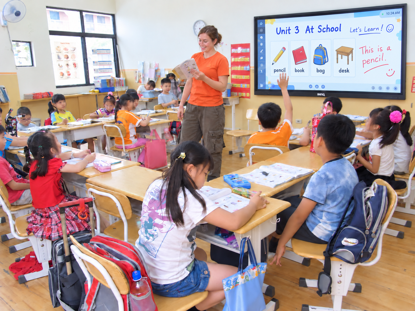 女教師拿著讀本與孩子進行英語閱讀活動